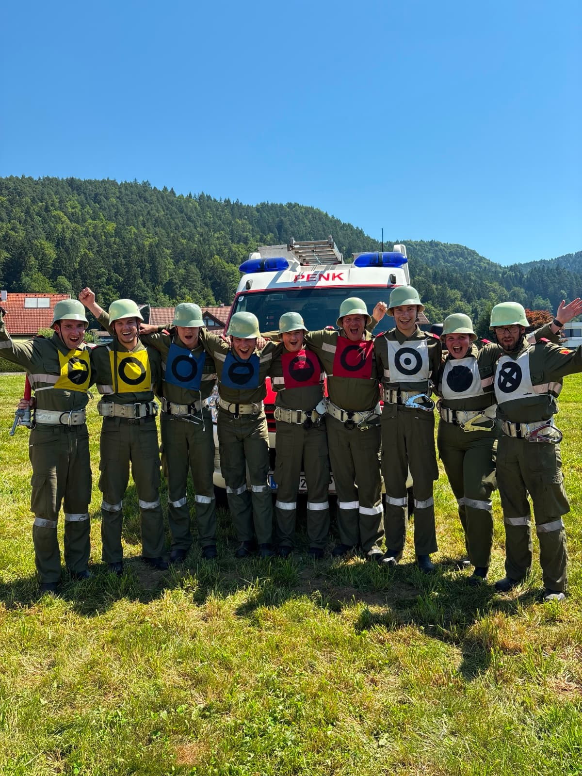 Jugendfeuerwehr Neumarkt am Wallersee mit Feuerwehrauto vor bewaldeter Bergkulisse